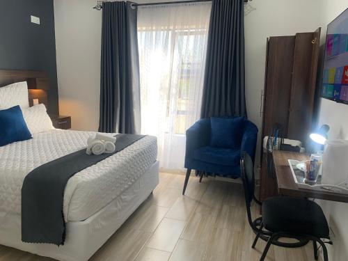 a bedroom with a bed and a blue chair at Mongi Guest House in Harare