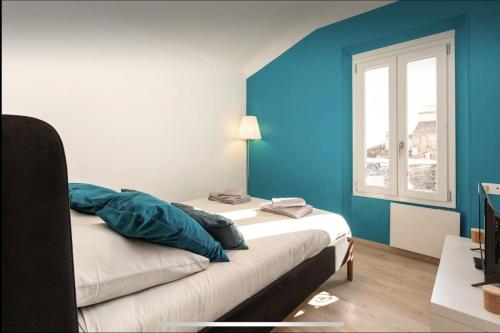 Cette chambre comprend un lit avec des murs bleus et une fenêtre. dans l'établissement Le Suquet - Château - Palais - Seaview - WIFI, à Cannes