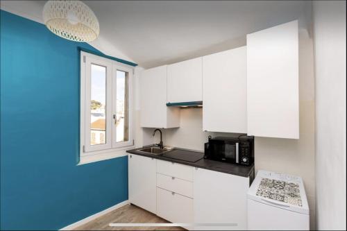 une cuisine avec des armoires blanches et un mur bleu dans l'établissement Le Suquet - Château - Palais - Seaview - WIFI, à Cannes