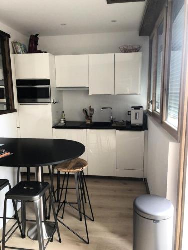 une cuisine avec des armoires blanches et une table et des chaises dans l'établissement Résidence Res.de L Oisans - APPARTEMENT ALPE D'HUEZ PROCHE CENTRE STATION MAE-2451, à Huez