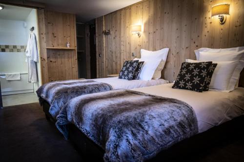 deux lits dans une chambre aux murs en bois dans l'établissement Les Chalets Du Cocoon - CHALET COCOON MAE-1611, à Aime La Plagne
