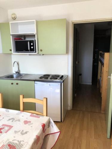 Il comprend une petite cuisine équipée d'une cuisinière et d'un évier. dans l'établissement Résidence Skisun - APPARTEMENT ALPE D'HUEZ CENTRE STATION MAE-2471, à Huez