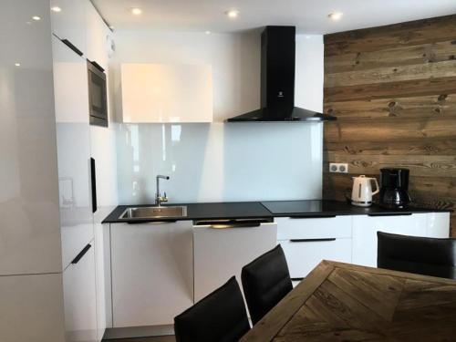 - une cuisine avec des placards blancs et un mur en bois dans l'établissement Résidence Taburle - APPARTEMENT ALPE D'HUEZ HAUT DE STATION MAE-2651, à Huez