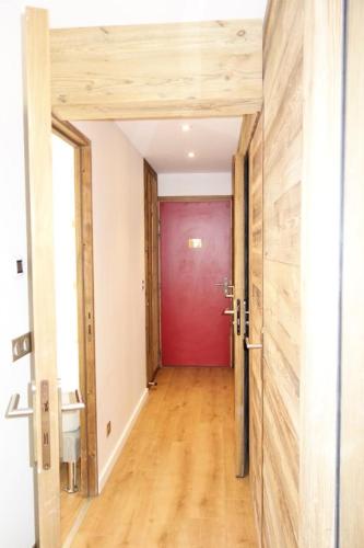 - un couloir avec une porte rouge et du parquet dans l'établissement Résidence Taburle - APPARTEMENT ALPE D'HUEZ HAUT DE STATION MAE-2651, à Huez