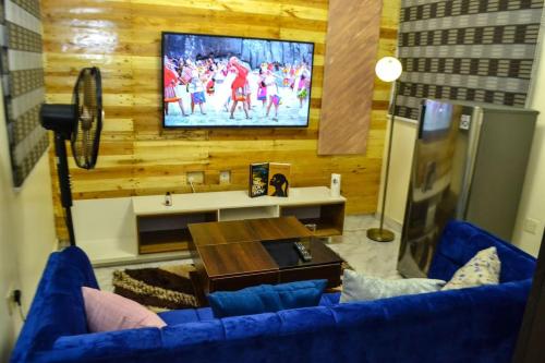 a living room with a blue couch and a tv at SEGXYCOLD VALLEY OASIS Stunning one-bedroom apartment in Ijaiye