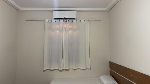 a bedroom with a white curtain and a bed at Hotel Nova Sorocabana in Brodósqui
