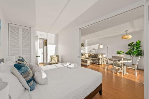 a white bedroom with a bed and a living room at Newly Renovated Oceanfront Waikiki- Ilikai Marina in Honolulu