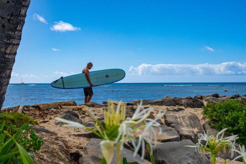 a man standing on a beach holding a surfboard at Newly Renovated Oceanfront Waikiki- Ilikai Marina in Honolulu