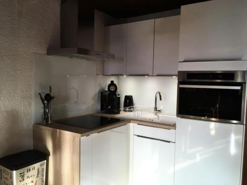 La cuisine est équipée de placards blancs et d'un four micro-ondes noir. dans l'établissement Résidence Marmottes - APPARTEMENT 3 PIECES ALPE D'HUEZ CENTRE STAITON MAE-2781, à Huez
