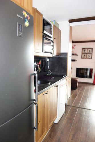 une cuisine avec un réfrigérateur noir et des armoires en bois dans l'établissement Résidence Skival - APPARTEMENT ALPE D'HUEZ QUARTIER DE L'ECLOSE MAE-2811, à Huez