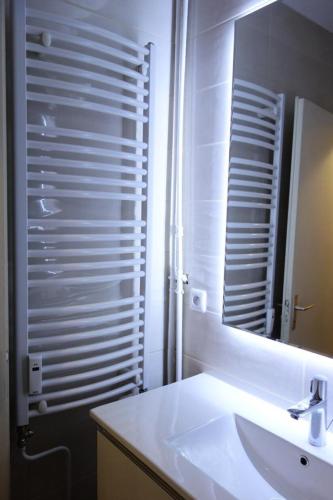 une salle de bain blanche avec un lavabo et un miroir dans l'établissement Résidence Pleiades - STUDIO 30m2 ROUTE DU SIGNAL CENTRE STATION MAE-2841, à Huez