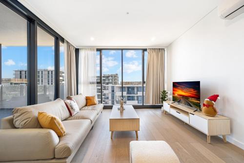 a living room with a couch and a tv at Modern 2B2BA Apartment in the Heart of Bankstown in Bankstown