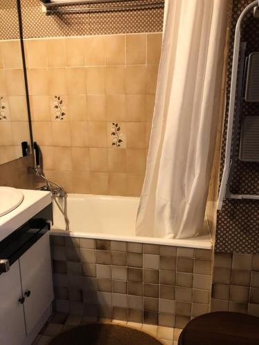La salle de bains est pourvue d'une baignoire avec rideau de douche. dans l'établissement Résidence Maison De L'alpe - APPARTEMENT ALPE D'HUEZ QUARTIER VIEL ALPE MAE-2981, à Huez