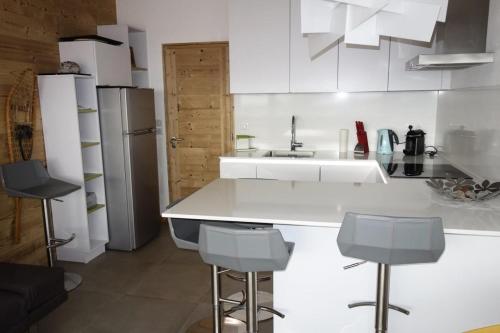 La cuisine est équipée d'un comptoir blanc et d'un réfrigérateur. dans l'établissement Résidence Milady - APPARTEMENT 2 PIECE + HALL HABITABLE ALPE D'HUEZ CENTRE STATION MAE-3001, à Huez