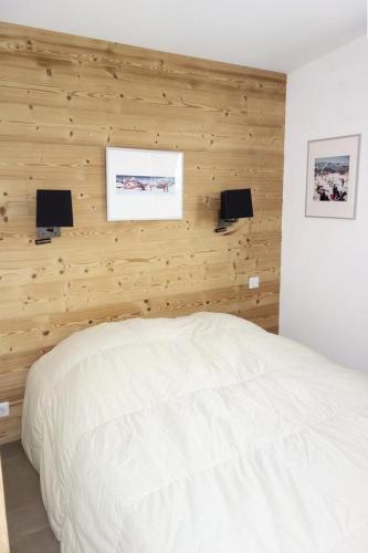 une chambre avec un lit blanc et des murs en bois dans l'établissement Résidence Milady - APPARTEMENT 2 PIECE + HALL HABITABLE ALPE D'HUEZ CENTRE STATION MAE-3001, à Huez