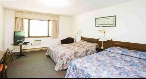 a hotel room with two beds and a television at Auberge Eldo Inn in Blind River