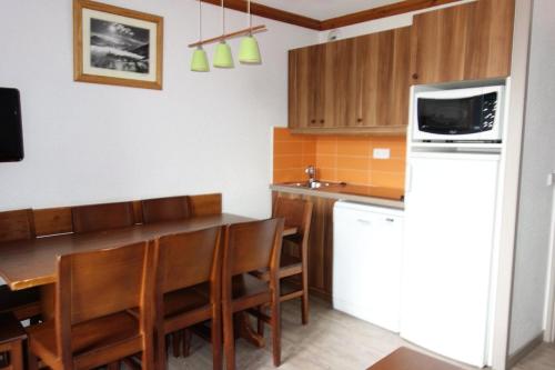 une cuisine avec une table et des chaises et un micro-ondes dans l'établissement Résidence Bergers P&v - APPARTEMENT ALPE D'HUEZ QUARTIER BERGERS MAE-3061, à Huez