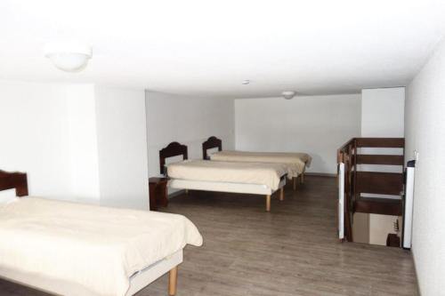 Cette chambre comprend 3 lits avec des draps blancs et du parquet. dans l'établissement Résidence Bergers P&v - APPARTEMENT ALPE D'HUEZ QUARTIER BERGERS MAE-3061, à Huez