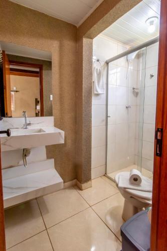 a bathroom with a sink and a shower and a toilet at Pousada Divino Canto - Olímpia in Olímpia