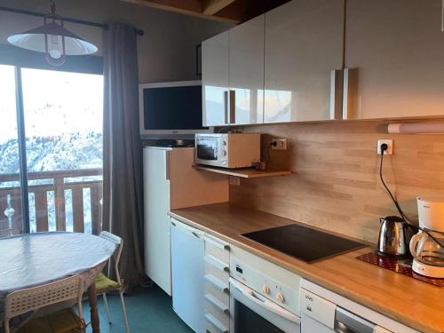 Il dispose d'un balcon et d'une cuisine avec un comptoir et une table. dans l'établissement Résidence Balcons D'huez - APPARTEMENT ALPE D'HUEZ QUARTIER ECLOSE MAE-3221, à Huez