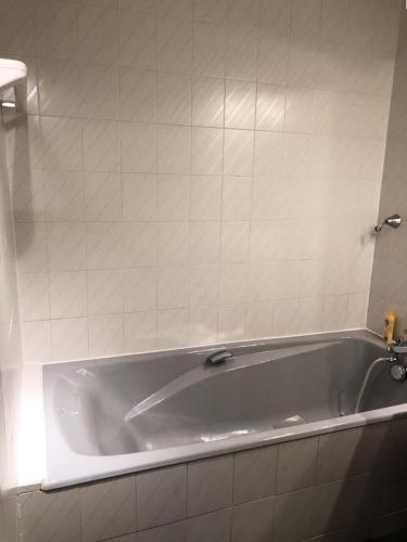 La salle de bains est pourvue d'une baignoire et d'un mur carrelé. dans l'établissement Résidence Horizon - Appartement 3 Pièces QUARTIER BERGERS-PIEDS DES PISTES-DEPART ESF MAE-3231, à Huez