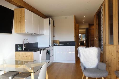 une cuisine avec une table en verre et des placards blancs dans l'établissement Résidence Menandiere - APPARTEMENT ALPE D'HUEZ CENTRE STATION MAE-3251, à Huez