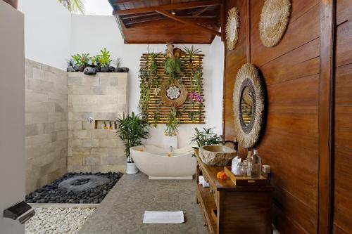 baño con bañera y algunas plantas. en Anantra Bali Eco Villa, en Ubud