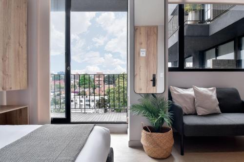 a bedroom with a bed and a chair and a window at Muttuo by Wynwood House in Bogotá