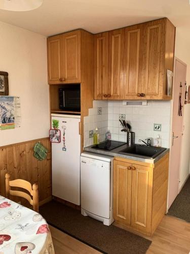 une cuisine avec des armoires en bois et un réfrigérateur blanc dans l'établissement Résidence Balcons D'huez - appartement 2 coins montagne ALPE D'HUEZ QUARTIER ECLOSE EST MAE-3441, à Huez