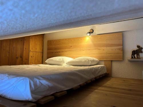 une chambre avec un grand lit avec une tête de lit en bois dans l'établissement Résidence Grand Sud - Studio de 20 m² avec mezzanine-ALPE D'HUEZ ECLOSE EST MAE-3481, à Huez