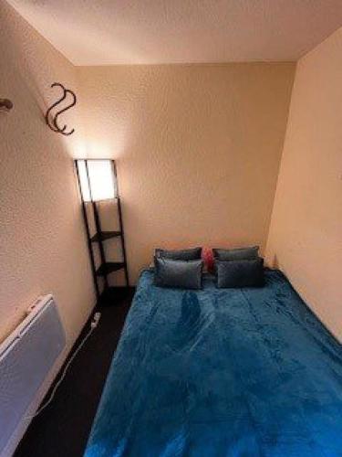 Cette chambre dispose d'un lit bleu et d'une fenêtre. dans l'établissement Résidence Grand Sud - Appartement de 23m²-ALPE D'HUEZ ECLOSE EST MAE-3521, à Huez