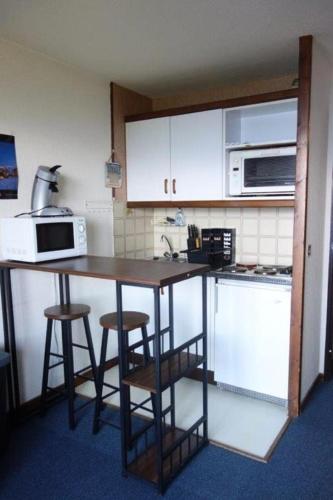 une cuisine avec une table et deux tabourets de bar dans l'établissement Résidence Solaires - APPARTEMENT ALPE D'HUEZ QUARTIER PASSEAUX MAE-3561, à Huez