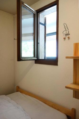 une chambre avec un lit et deux fenêtres dans l'établissement Résidence Solaires - APPARTEMENT ALPE D'HUEZ QUARTIER PASSEAUX MAE-3561, à Huez