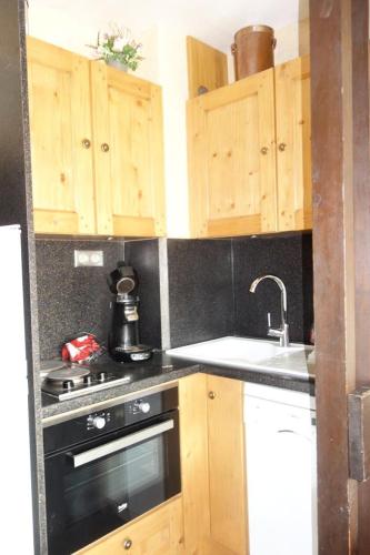 - une cuisine avec des placards en bois, une cuisinière et un évier dans l'établissement Résidence Obiou - APPARTEMENT ALPE D'HUEZ HAUT DE STATION MAE-3611, à Huez
