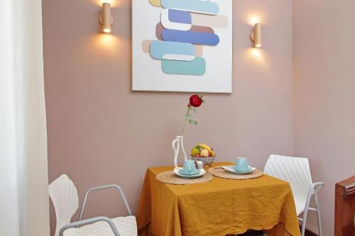a dining room table with a yellow tablecloth and white chairs at Villa Gisi Guest House in Fiumicino