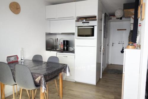 une cuisine avec une table et des placards blancs dans l'établissement Résidence Balcons D'huez - APPARTEMENT ALPE D'HUEZ QUARTIER DE L'ECLOSE MAE-3601, à Huez