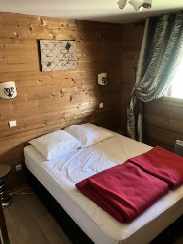 un lit dans une chambre avec un mur en bois dans l'établissement Chalet Alpina - APPARTEMENT ALPE D'HUEZ QUARTIER HAUT DE STATION MAE-3671, à Huez