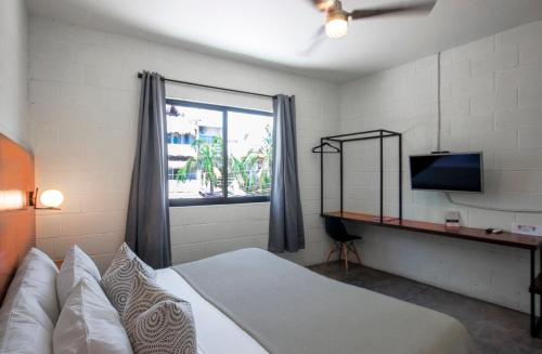 a bedroom with a bed and a television and a window at Casa Pia in Sayulita