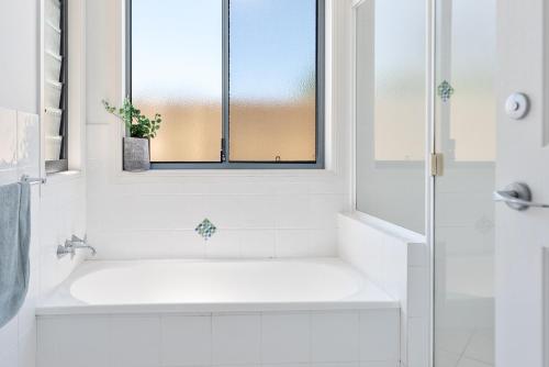 a bathroom with a white tub and a window at Sunrise on Terrace Unit 3, 21 Terrace Street Evans Head in Evans Head