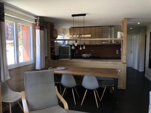 une cuisine avec une table en bois et quelques chaises dans l'établissement Résidence Sarenne - APPARTEMENT 3 Pièces ALPE DHUEZ CENTRE STATION MAE-3031, à Huez