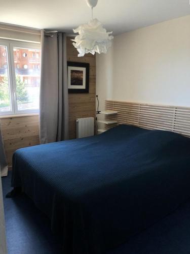 - une chambre avec un lit bleu et un lustre dans l'établissement Résidence Sarenne - APPARTEMENT 3 Pièces ALPE DHUEZ CENTRE STATION MAE-3031, à Huez