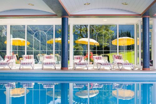 a pool with chairs and tables and umbrellas at Hotel Leitner in Mittelberg