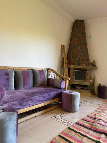 a living room with a purple couch and a fireplace at Tissi House in Tahannout