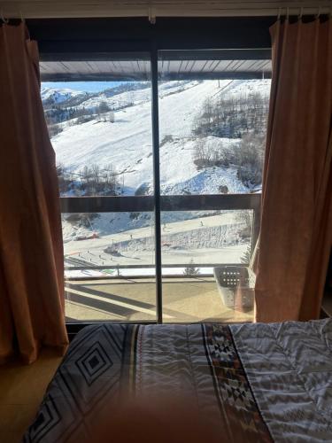 een slaapkamerraam met uitzicht op een besneeuwd veld bij La montagne in Villarembert