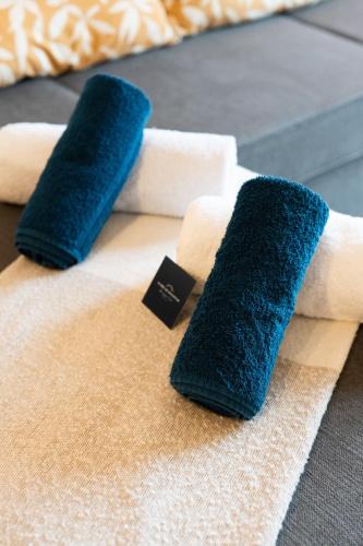 - un lit avec 2 serviettes bleues et blanches dans l'établissement Au Bercail Mâconnais - Hypercentre - Proche gare - Confort - 8 personnes, à Mâcon