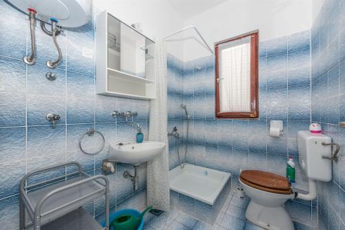 a blue tiled bathroom with a toilet and a sink at Apartment Mili in Betina