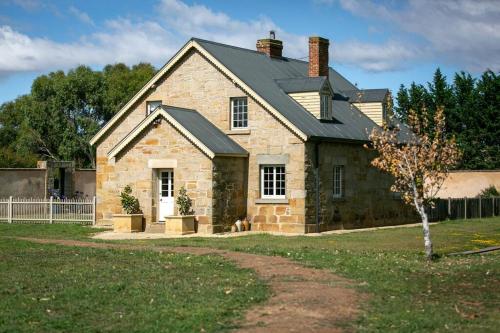 a brick house with a dog sitting in front of it at Historic Sandstone Ross Farmhouse in Ross