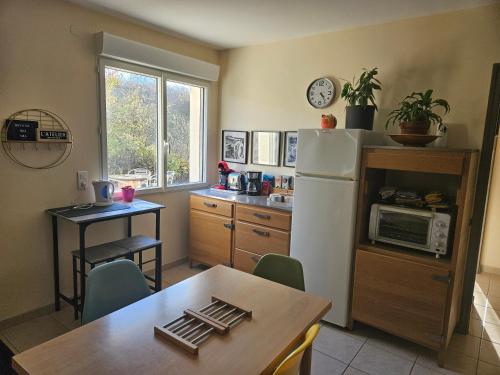 une cuisine avec une table et un réfrigérateur dans l'établissement l'atelier, à Saint-Lubin-en-Vergonnois
