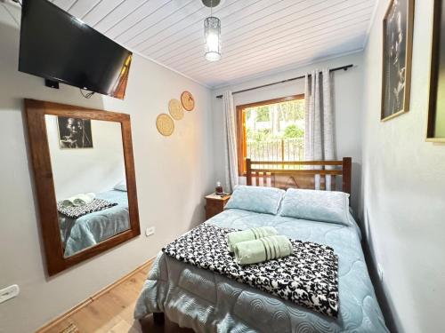 a bedroom with a bed and a mirror at Casa Conforto 8 min do centrinho in Campos do Jordão