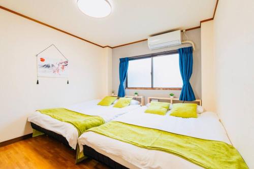 two beds in a room with blue curtains at Mont Hotel Higashi mikuni in Osaka